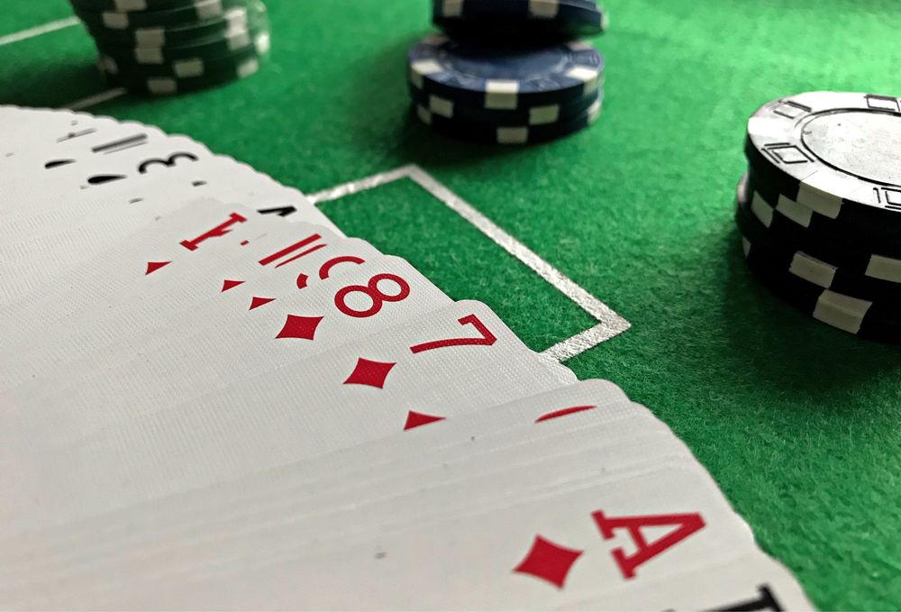 Kartu remi dan chip poker di atas meja felt hijau